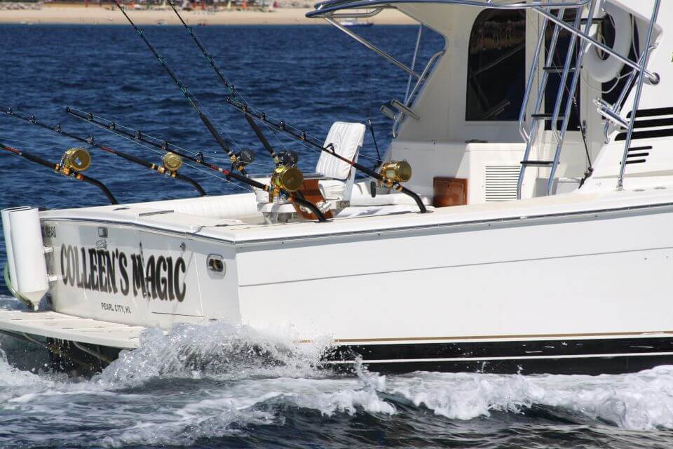 Back of our Cabo Fishing Charters yacht with 5 fishing poles cruising on ocean in Cabo San Lucas
