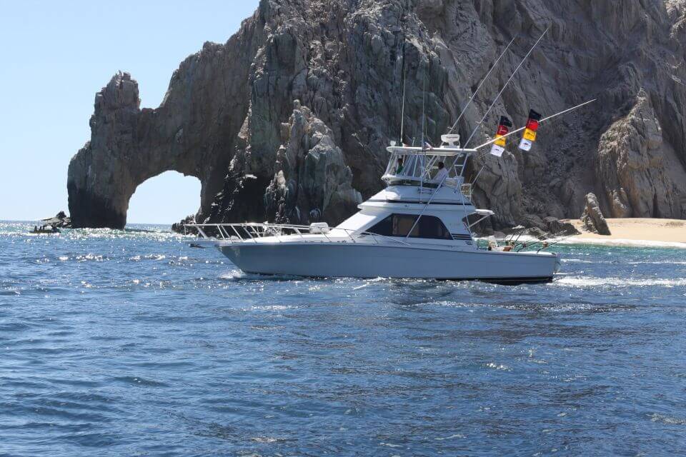 Cabo Fishing Charters yacht Colleens Magic sitting on ocean with Cabo San Lucas Arch in the background